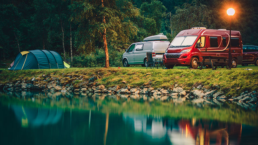 Parked vans standing in front of a lake in a jungle.